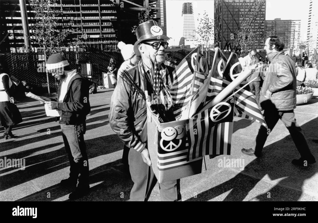 San Francisco, California:  c. 1968 A man with smiley face buttons and American flags with the peace symbol during an anti Vietnam war demonstration. Stock Photo