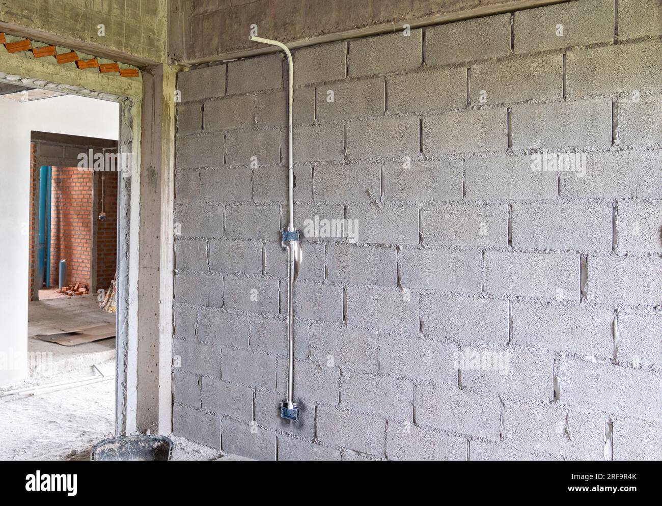 Iron blocks that were buried in the walls of the house. with a white PVC pipe running down. Preparing for the electrical installation in the building. Stock Photo