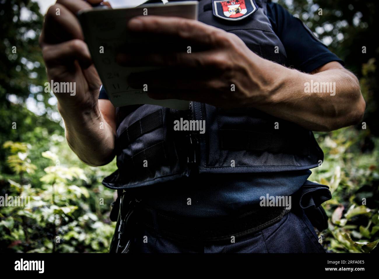 Berlin, Germany. 01st Aug, 2023. An employee of the public order office writes notes in a pad during a control in Weinbergspark. The inspections by the public order office are concerned with violations of the Green Spaces Act and violations of the leash requirement for dogs. Credit: Carsten Koall/dpa/Alamy Live News Stock Photo