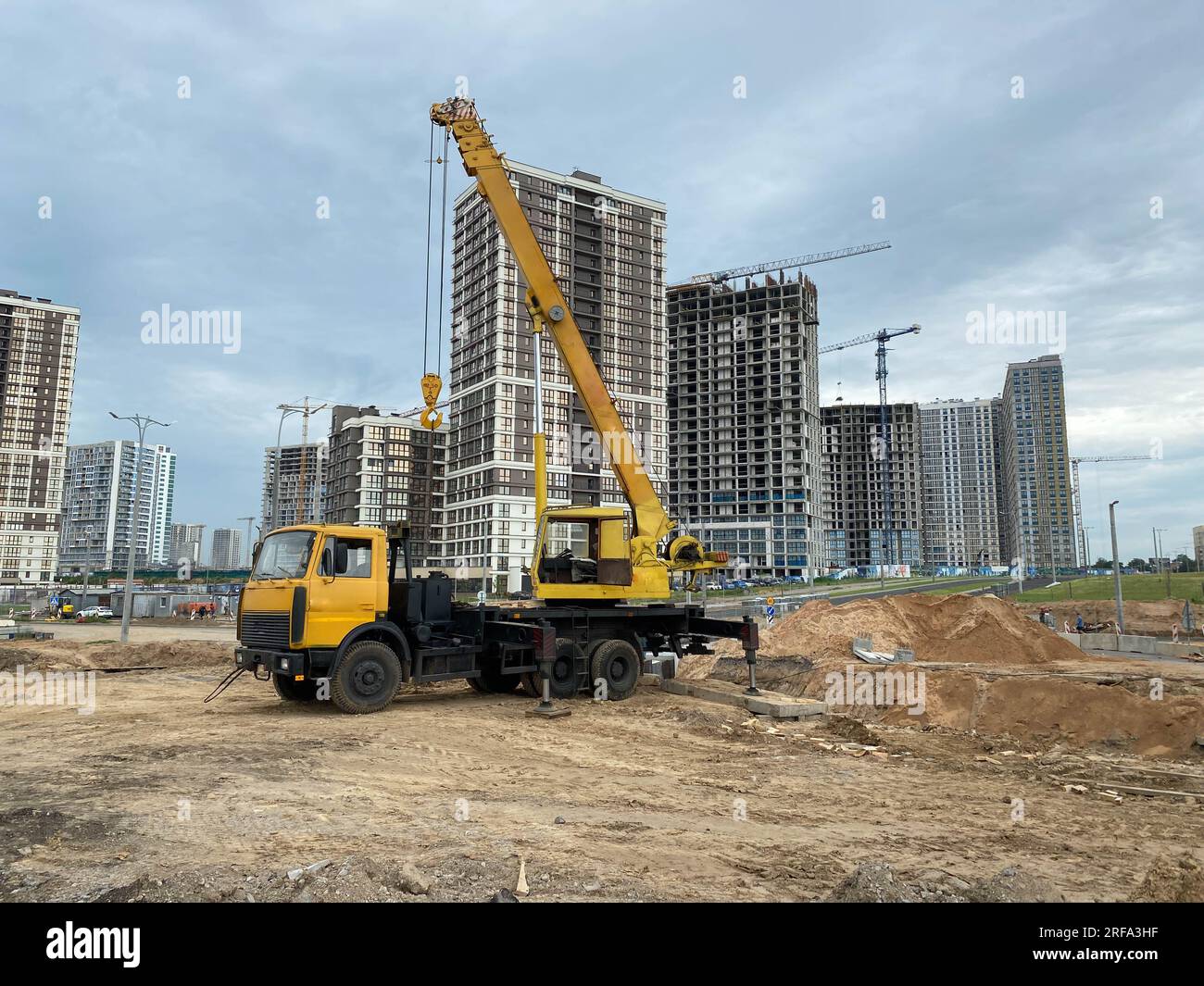Large yellow mobility modern industrial construction crane mounted on a truck is used in the construction of new housing, houses, buildings in a big c Stock Photo