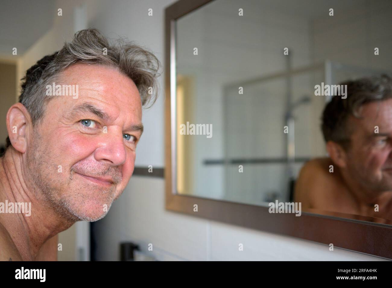 Nice attractive man early in the morning in the bathroom looks friendly at the camera Stock Photo