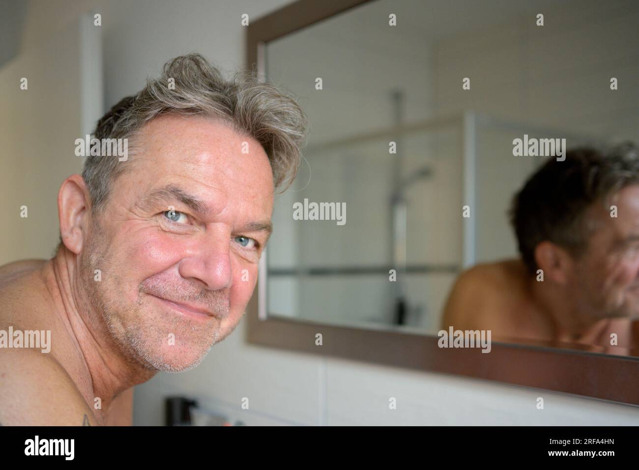 Nice attractive man early in the morning in the bathroom looks friendly at the camera Stock Photo