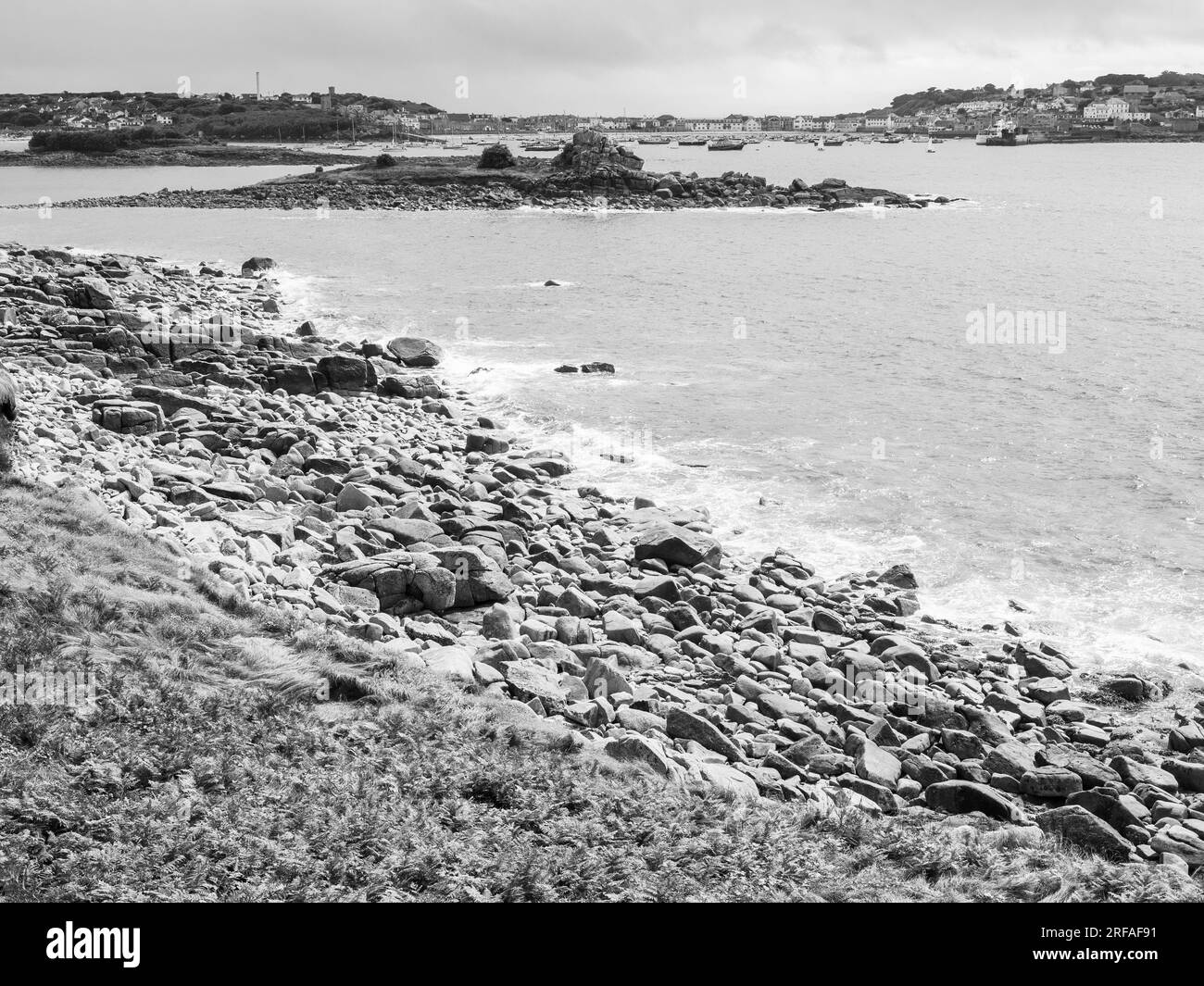 Black and White Landscape of Rocky Coastline, with Hugh Town, St Marys, Isles of Scilly, Cornwall, England, UK, GB. Stock Photo