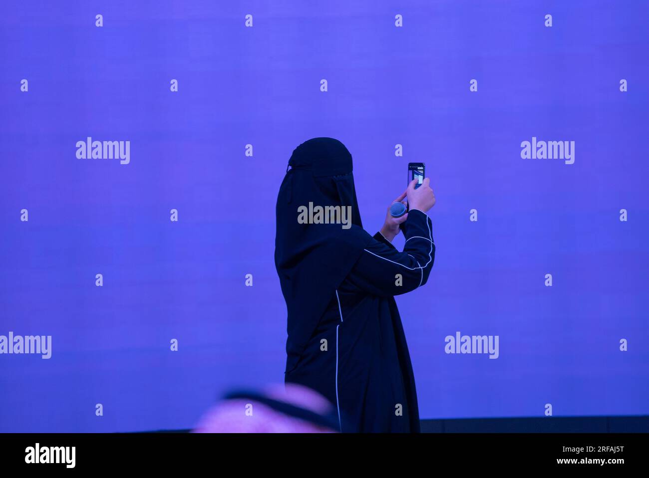 A Saudi woman takes pictures with her mobile phone in a business meeting Stock Photo