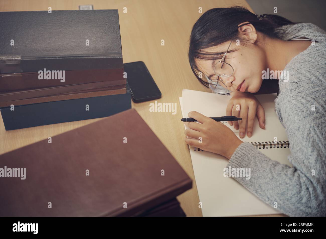 Tired student girl with glasses lying on books in library Stock Photo ...
