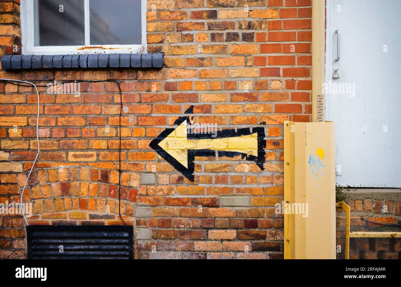 Arrow painted on building pointing to the left Stock Photo