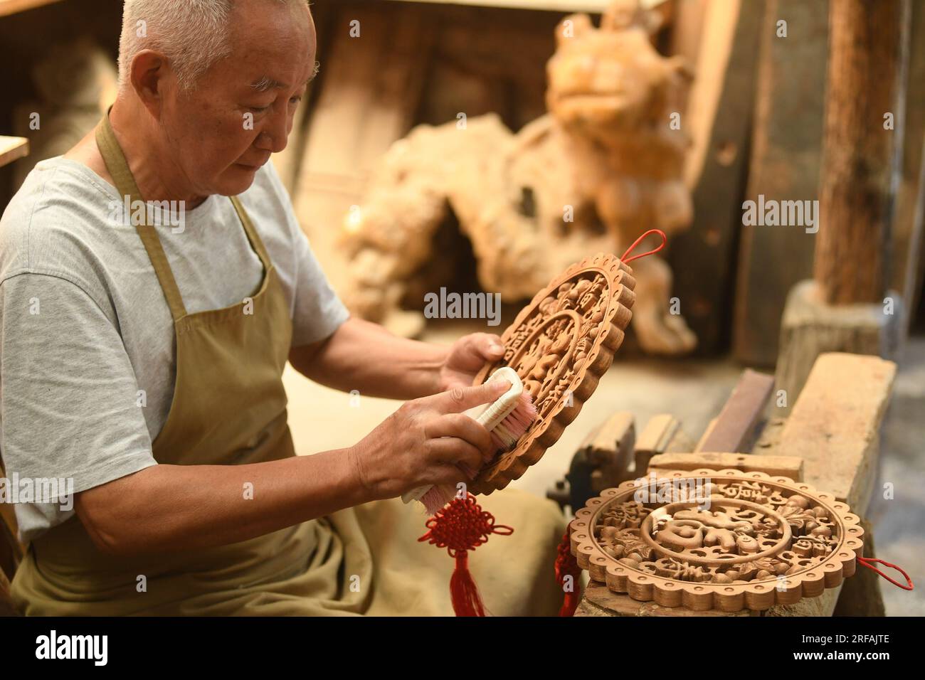 Jinhua, China's Zhejiang Province. 1st Aug, 2023. A carpenter cleans an artwork in Zhuge Village of Lanxi City, east China's Zhejiang Province, Aug. 1, 2023. The Zhuge Village, a historic gem with over 300 ancient buildings dating back to Ming and Qing dynasties (1368-1911), is home to descendents of Zhuge Liang, a renowned military strategist in the Three Kingdom Period (220-280). The village has made concerted efforts to preserve the ancient heritages and develop tourism, receiving over 500,000 visitors annually. Credit: Weng Xinyang/Xinhua/Alamy Live News Stock Photo