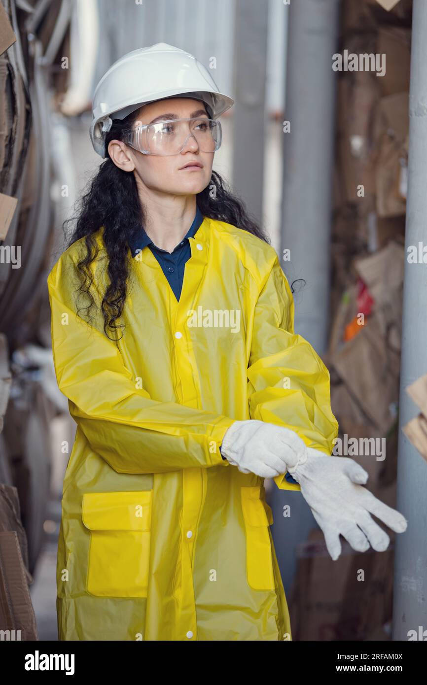 Long-haired inspector putting on gloves helps sort waste Stock Photo