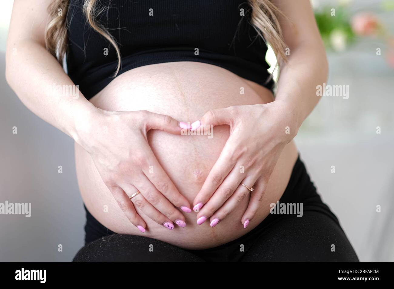 Mother love, pregnant woman with big belly advanced pregnancy resting  sitting on sofa at home making heart hands Stock Photo - Alamy