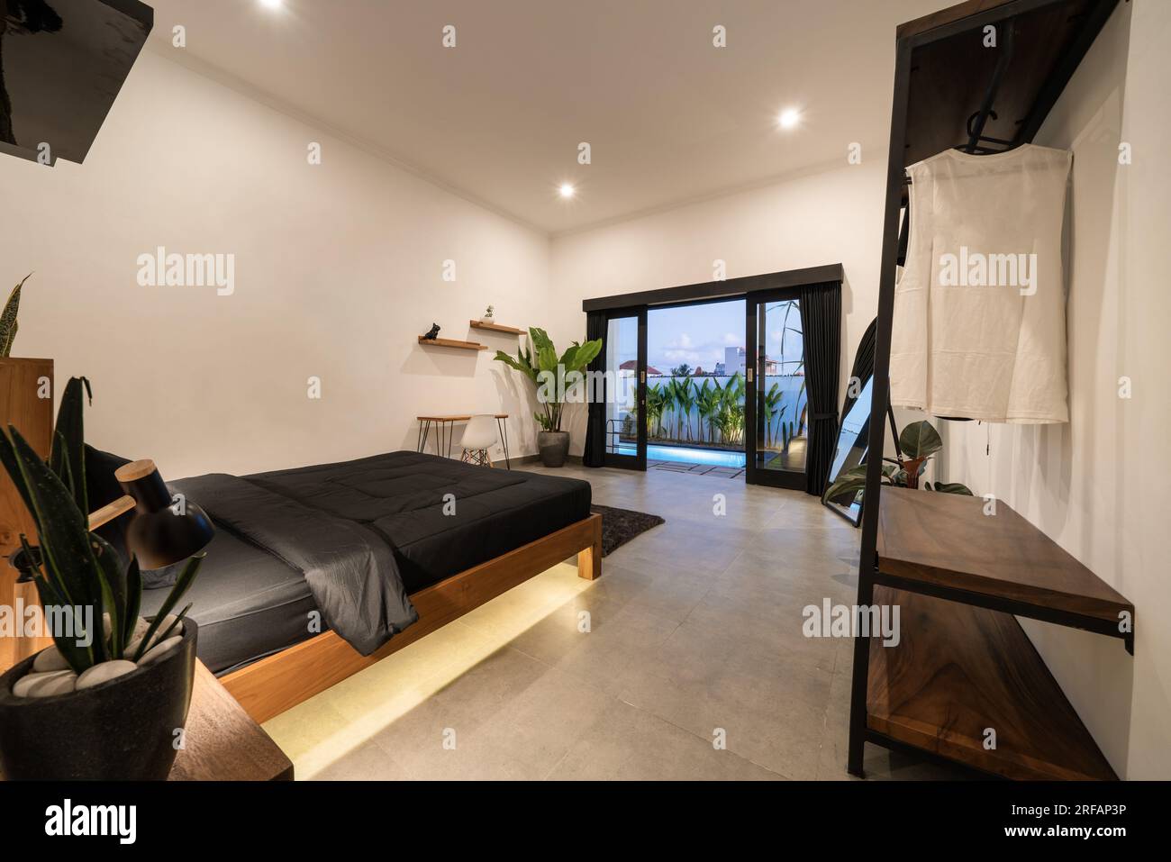Luxury white bedroom with modern wooden bed in loft style interior design room. Stock Photo