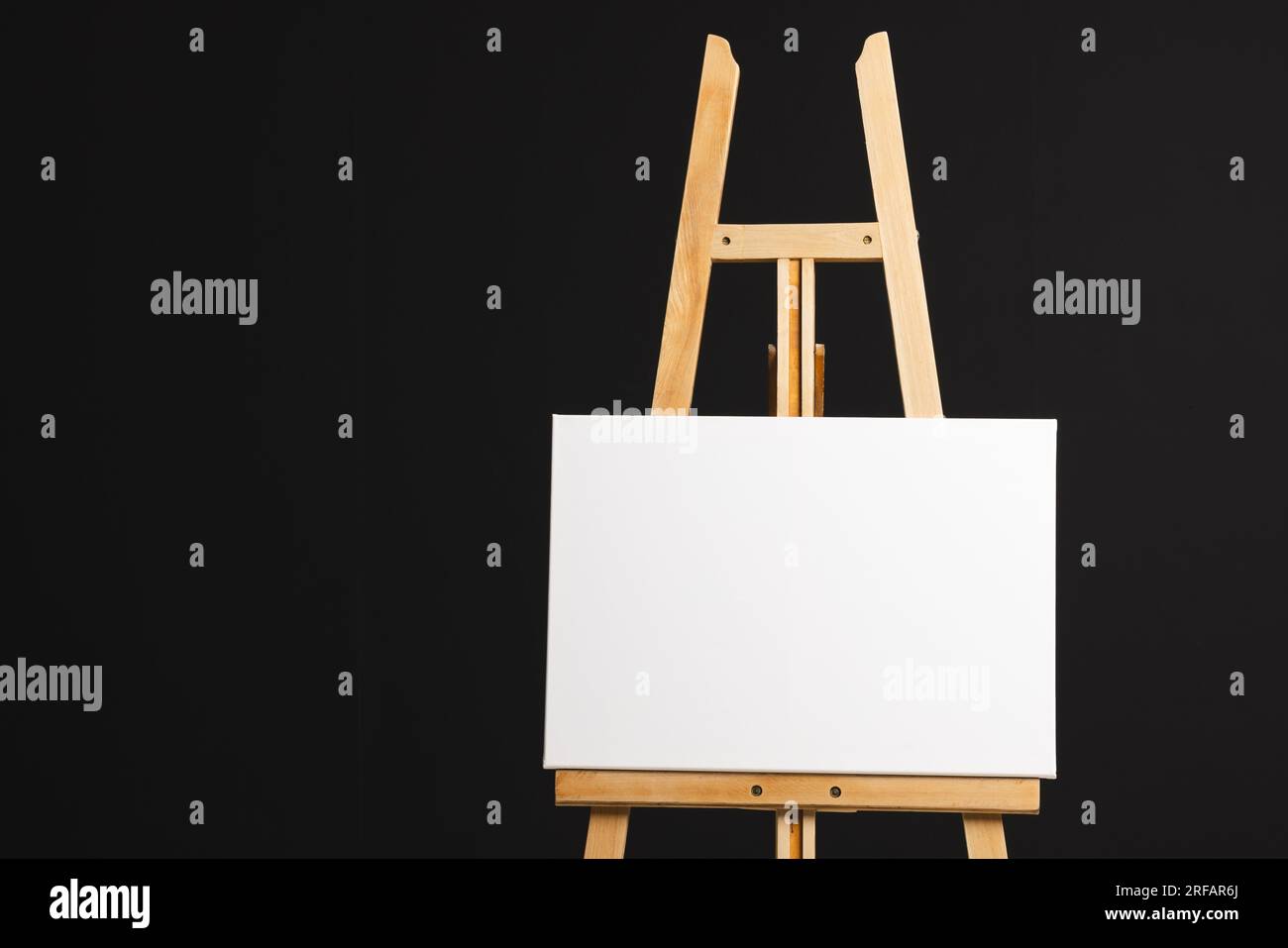 White canvas on wooden easel and copy space on black background Stock ...