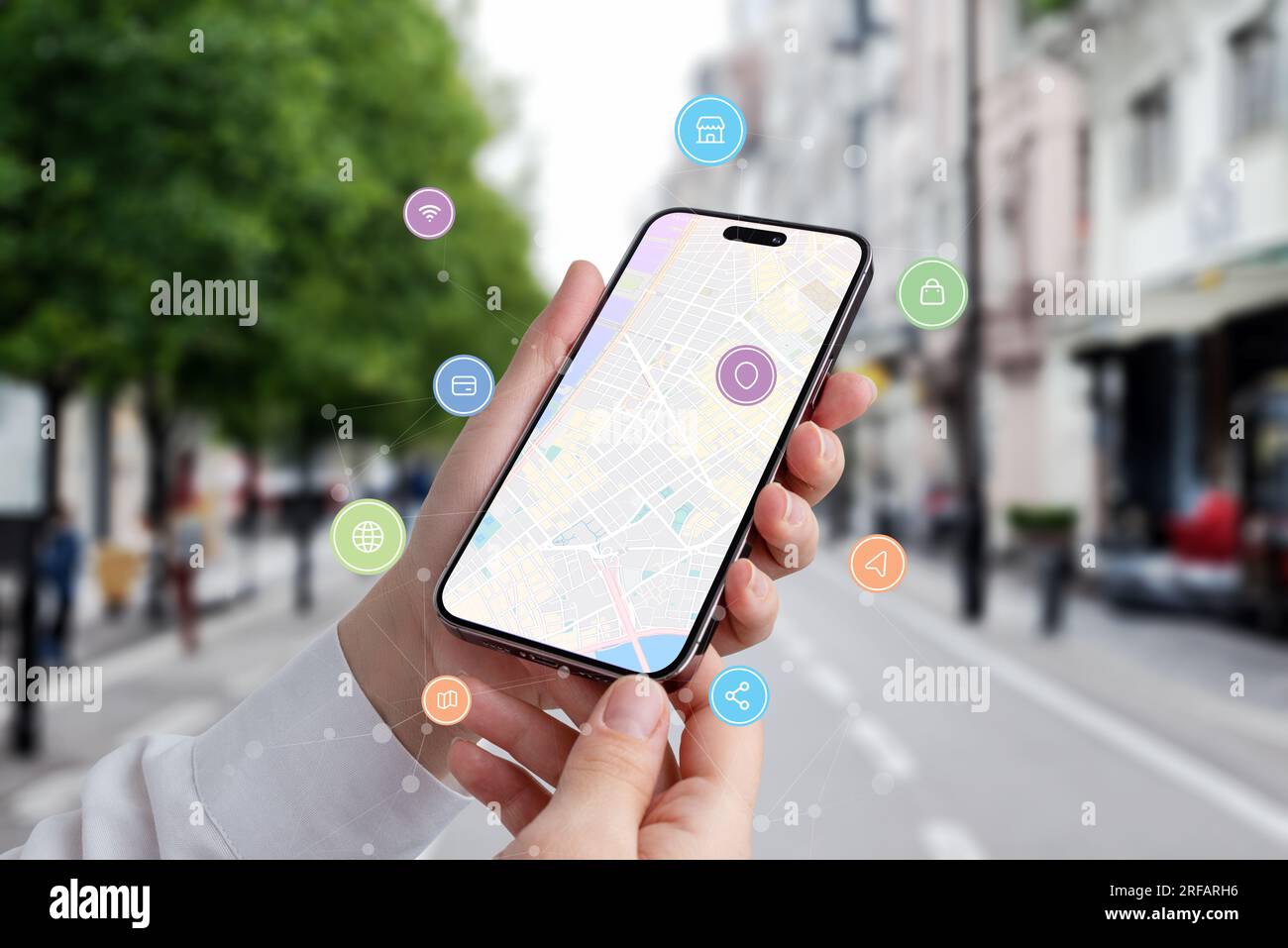 Find a location via a phone concept. Map of city on phone display with icons and network nodes flying arround Stock Photo