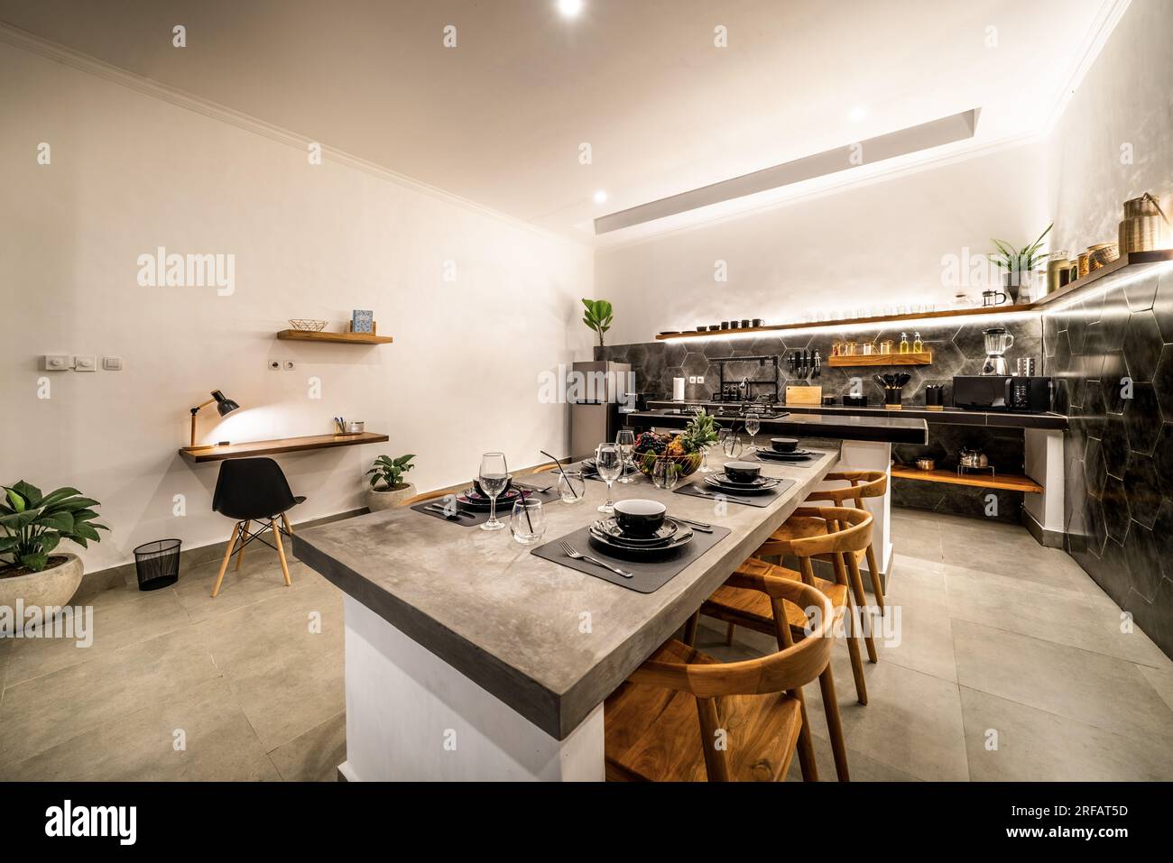 modern kitchen with appliances. Subtle lighting. dining table made of polished concrete. Stock Photo