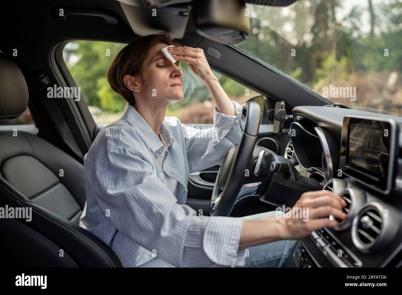 Woman drives car with broken air conditioner in hot weather wipes sweat