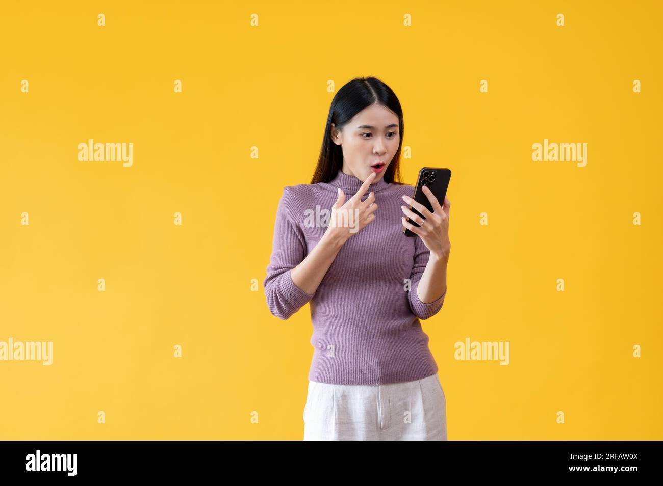An attractive Asian woman is looking at her smartphone screen with a ...