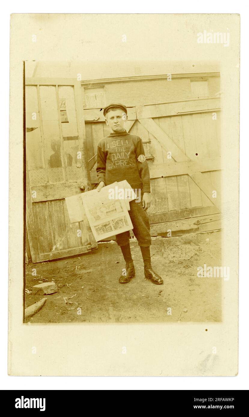 Original Titanic era postcard of newspaper seller boy, teenaged years,  wearing an "I sell the Daily Express jumper" but holding Daily Mirror Licence no 98. possibly  Liverpool circa 1912 U.K. Stock Photo