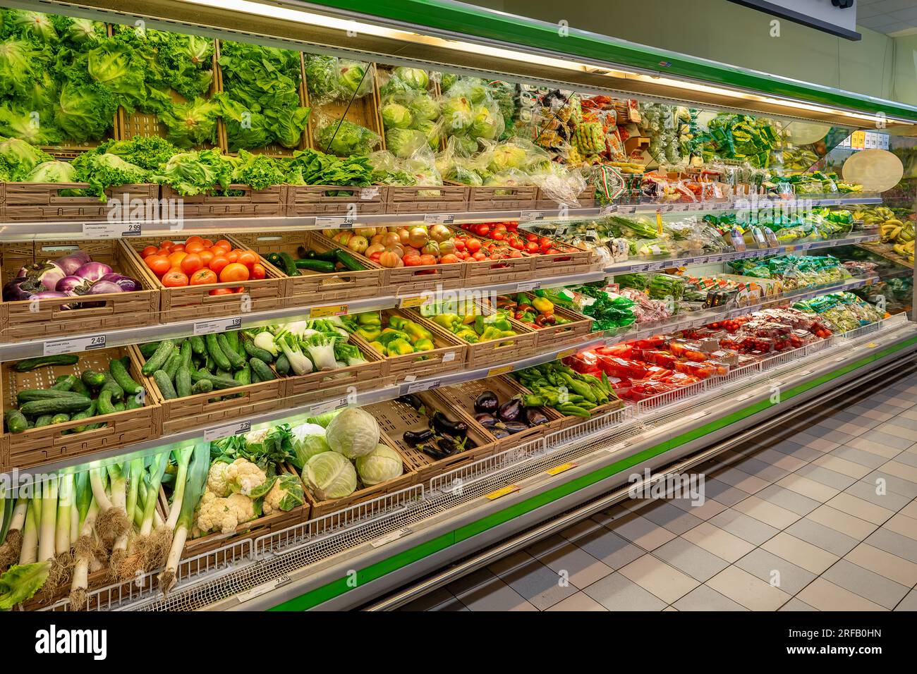 Italy - 01 August 2023: Fresh vegetables in crates and ready-to-eat packages displayed on the refrigerated counter shelves for sale in an Italian supe Stock Photo