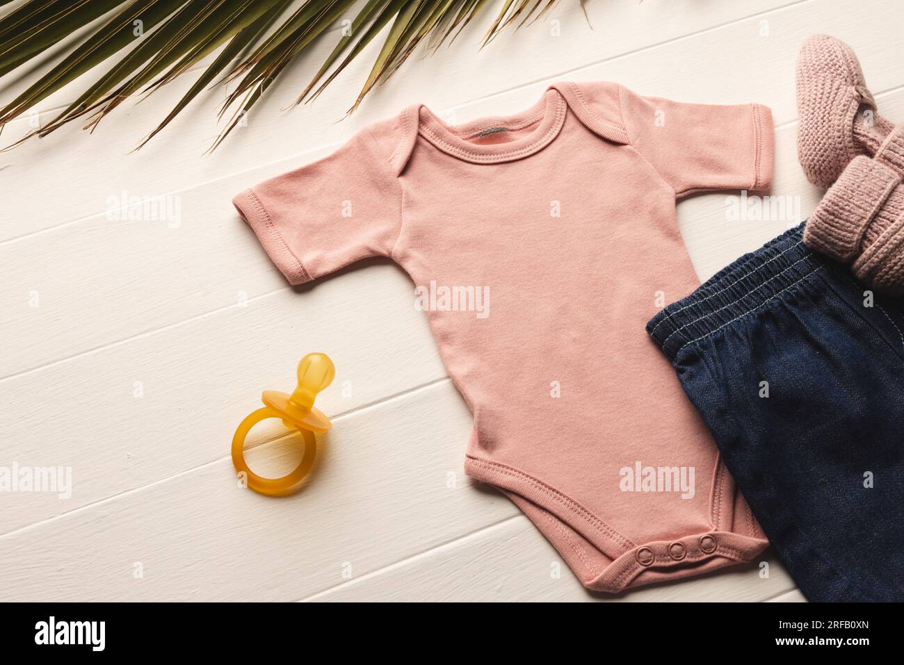 Flat lay of pink baby grow, shorts, dummy and pink booties with copy space on white background Stock Photo