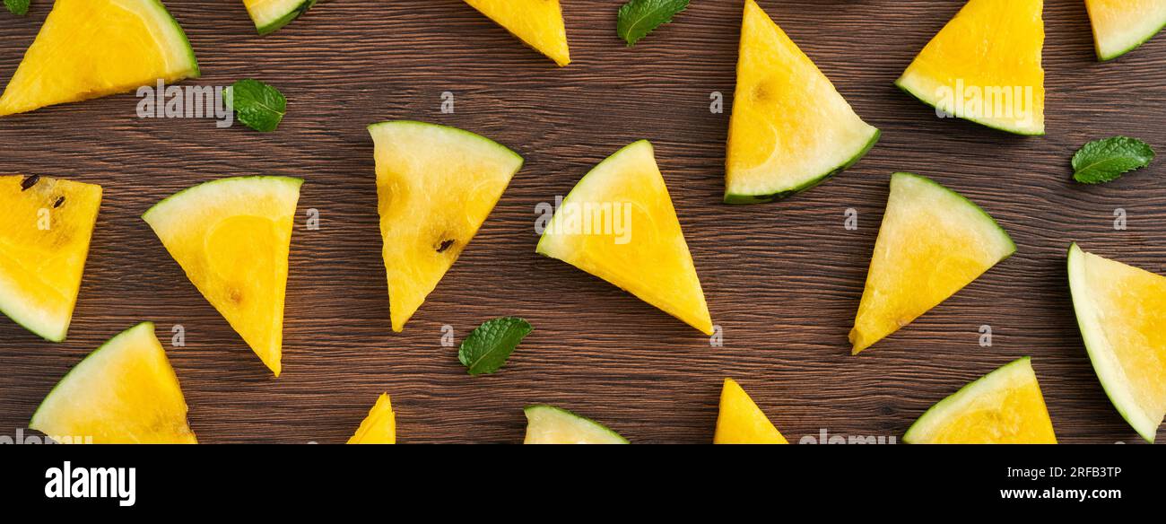 Sliced yellow golden watermelon pattern flat lay on wooden table background. Stock Photo