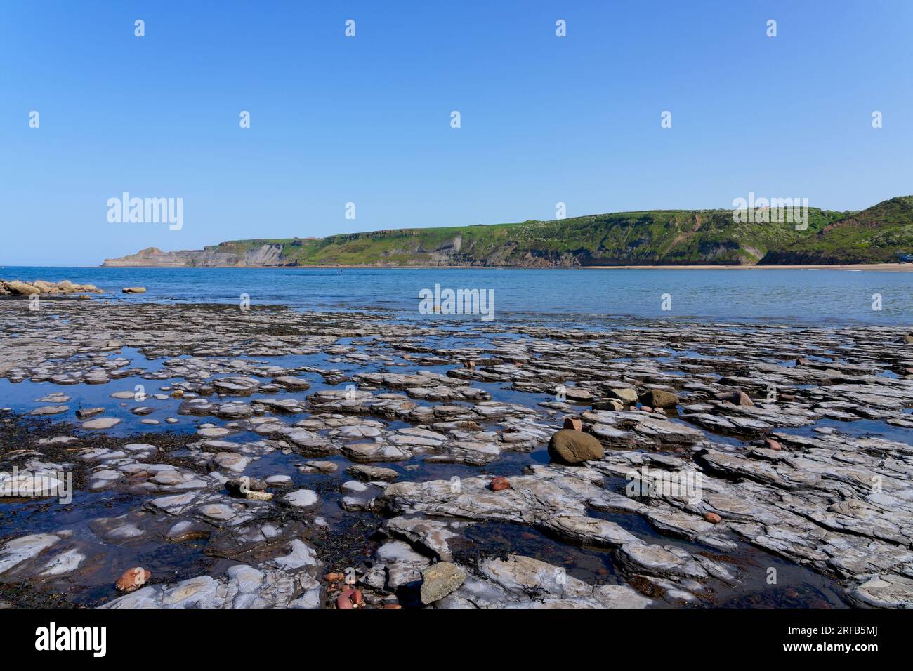 Cloudless blue sky on a spring afternoon among the rockpools of Runswick Bay beach. Stock Photo