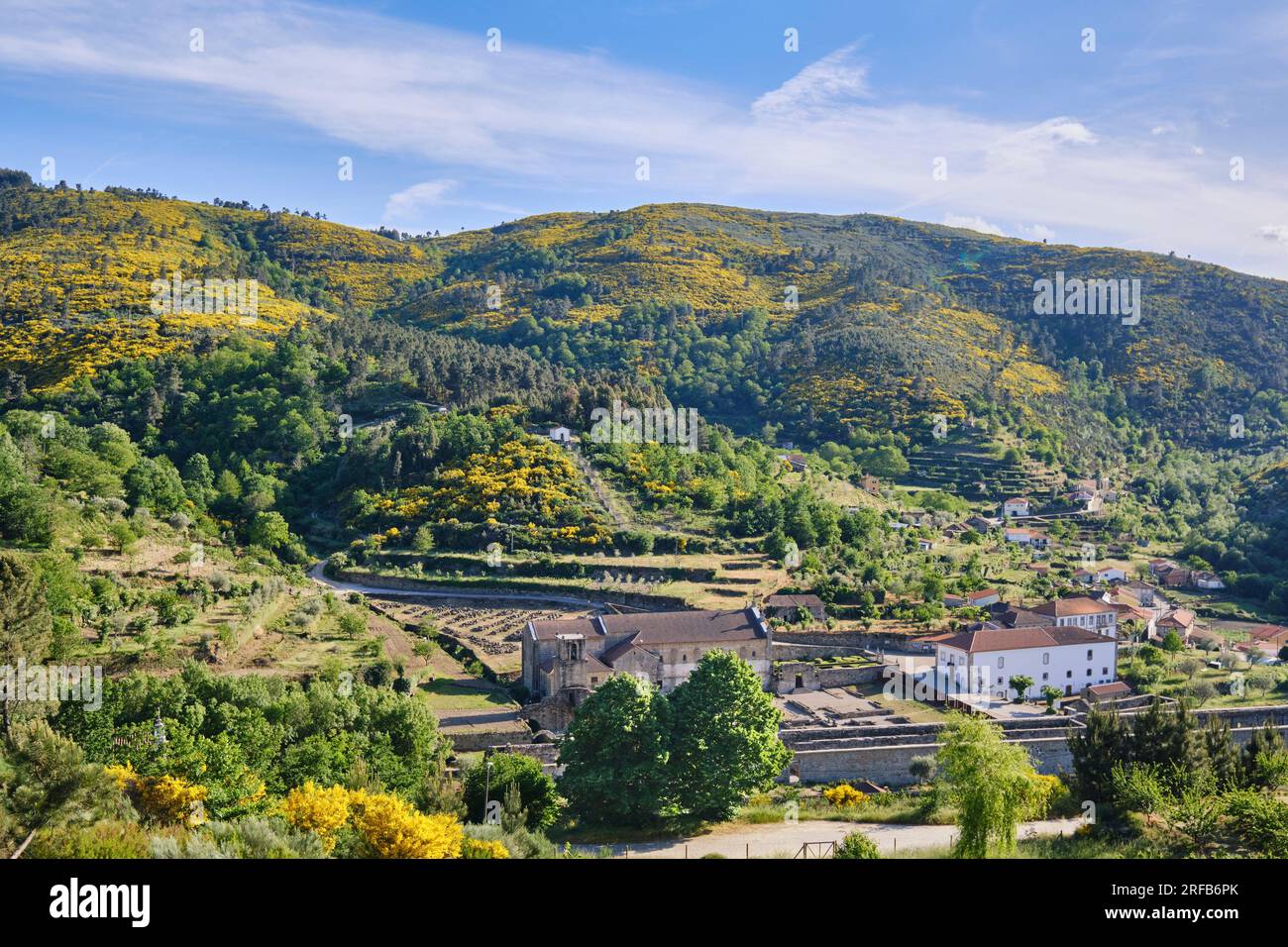 Monastery of Sao Joao de Tarouca and the surrounding mountains coloured in yellow because of the broom in bloom. Tarouca, Portugal Stock Photo