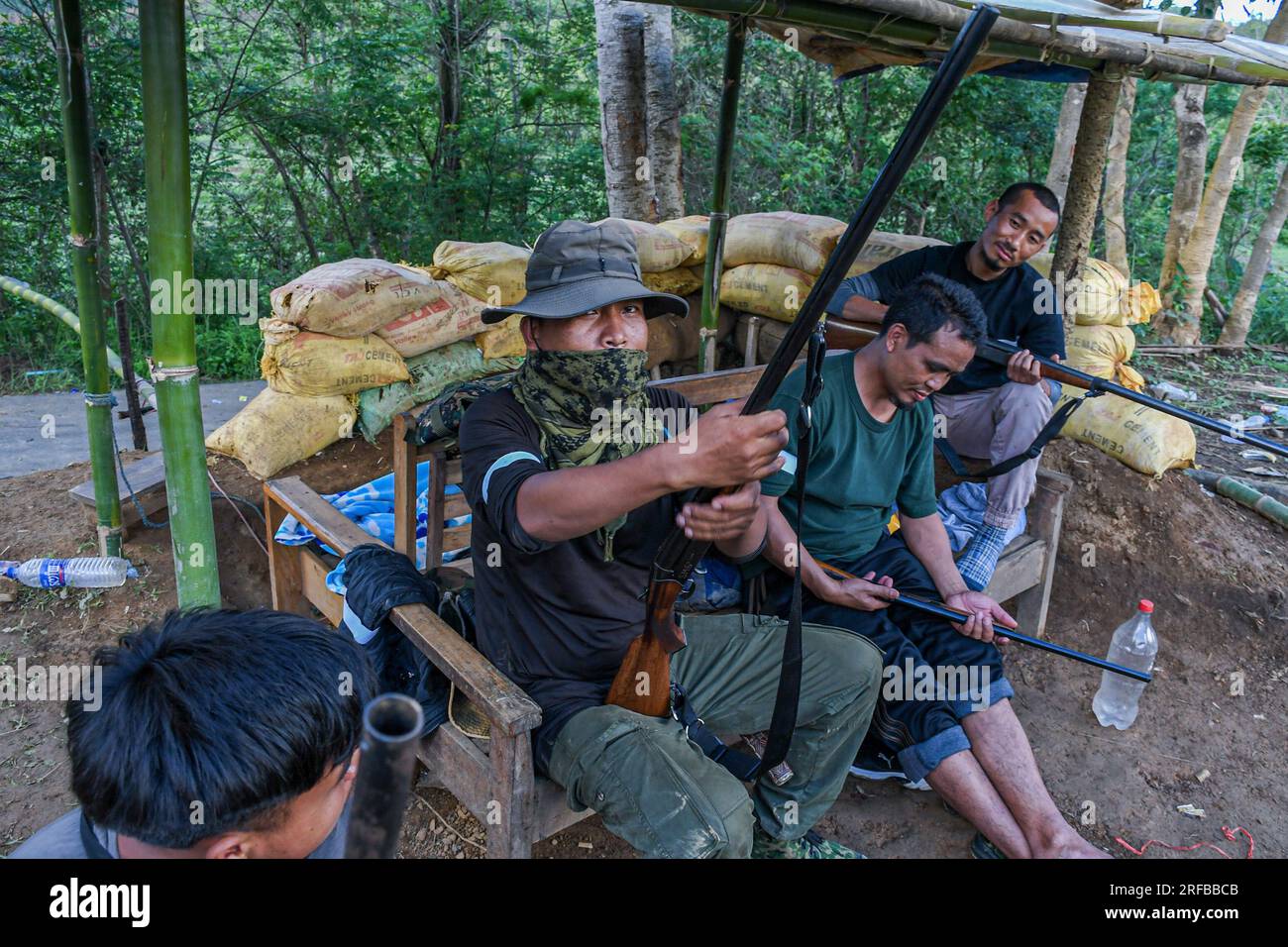 An armed Kuki man demonstrates a rifle while guarding the checkpoint at ...