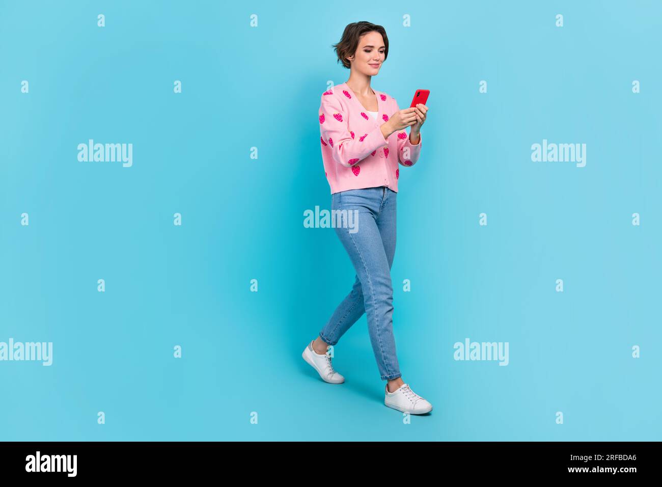 full-body-length-cadre-of-young-friendly-woman-wear-pink-cardigan-denim-jeans-try-chat-gpt-smartphone-isolated-on-blue-color-background-2RFBDA6.jpg