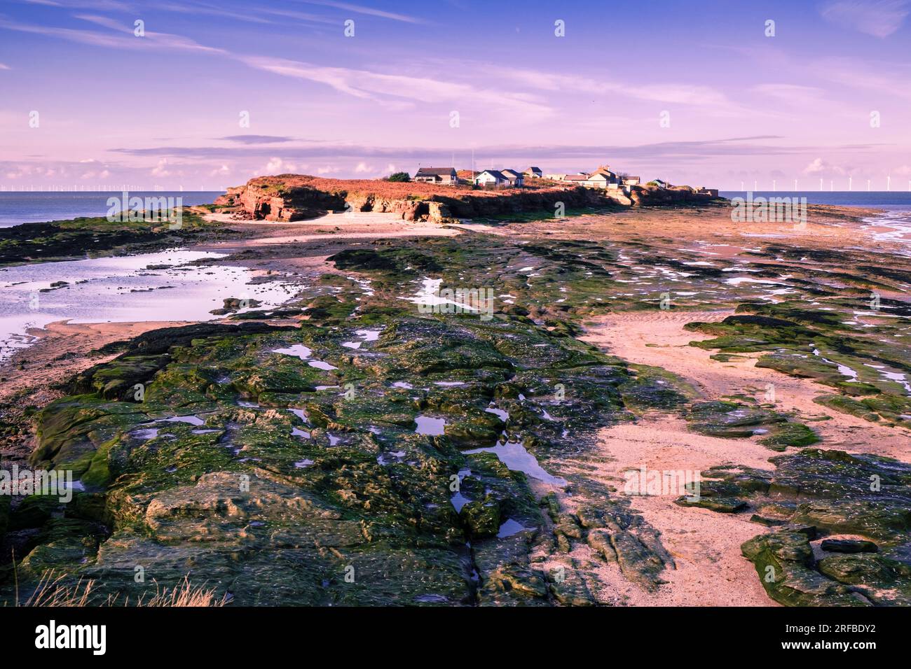 View across rock pools to Hilbre Island from Little Hilbre island in Dee Estuary at low tide. West Kirby, Wirral Peninsula, Merseyside, England, UK Stock Photo