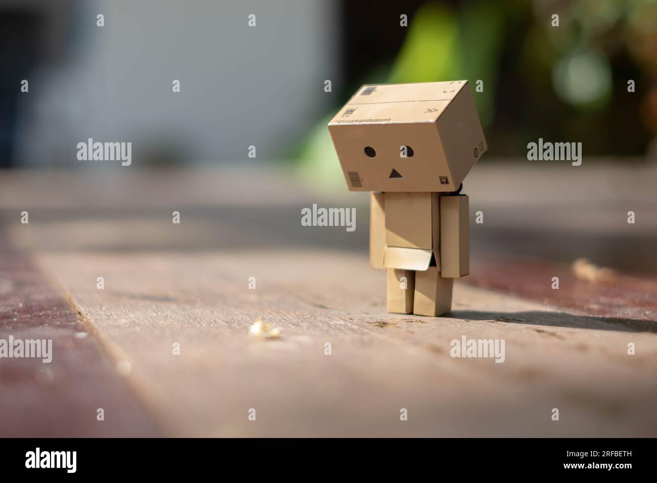 Small wooden toy robot danbo lonely isolated alone sad character, wood floor outdoor cartoon box anime happy art concept nature summer, brown doll cut Stock Photo