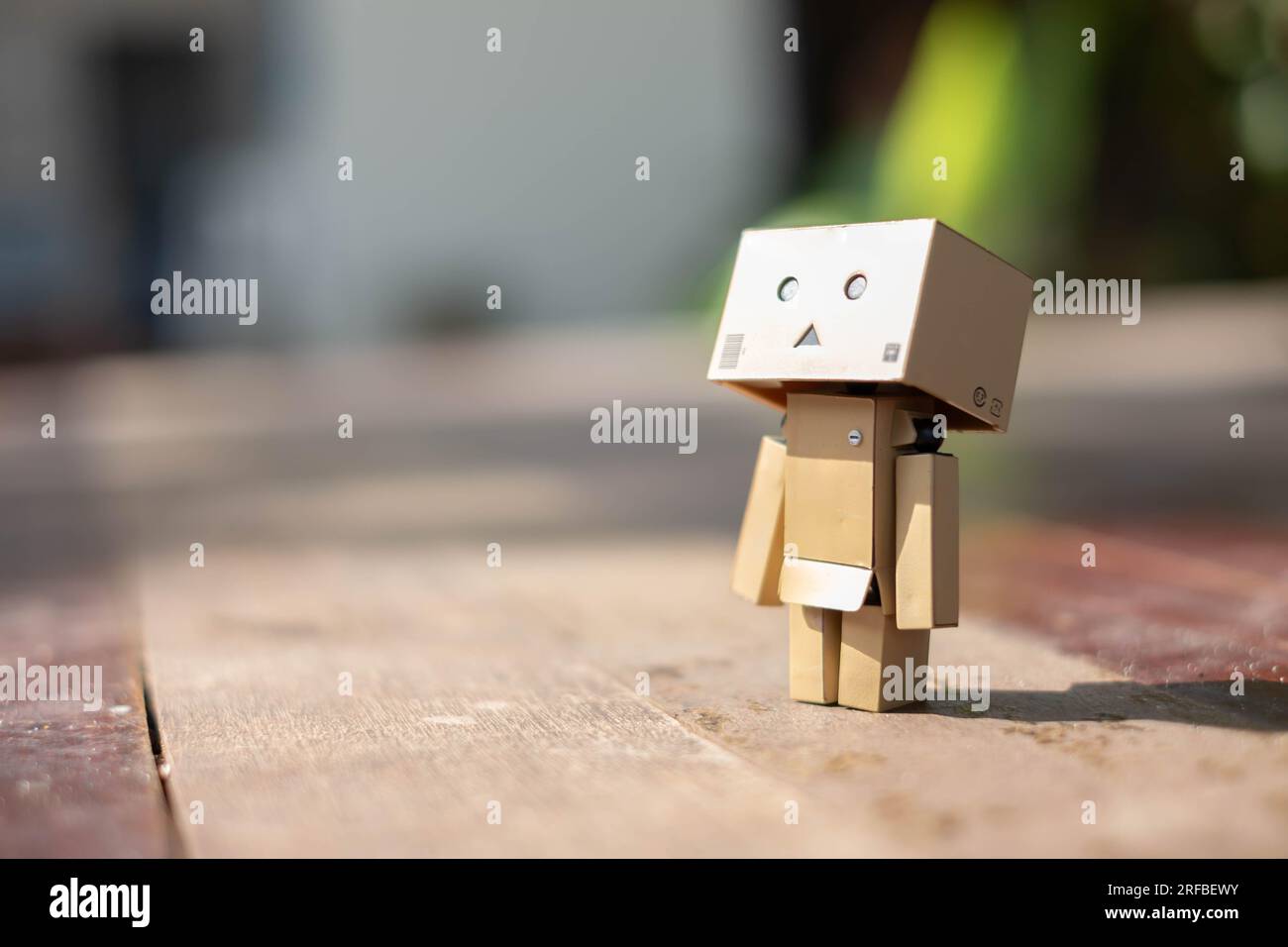 Small wooden toy robot danbo lonely isolated alone sad character, wood floor outdoor cartoon box anime happy art concept nature summer, brown doll cut Stock Photo