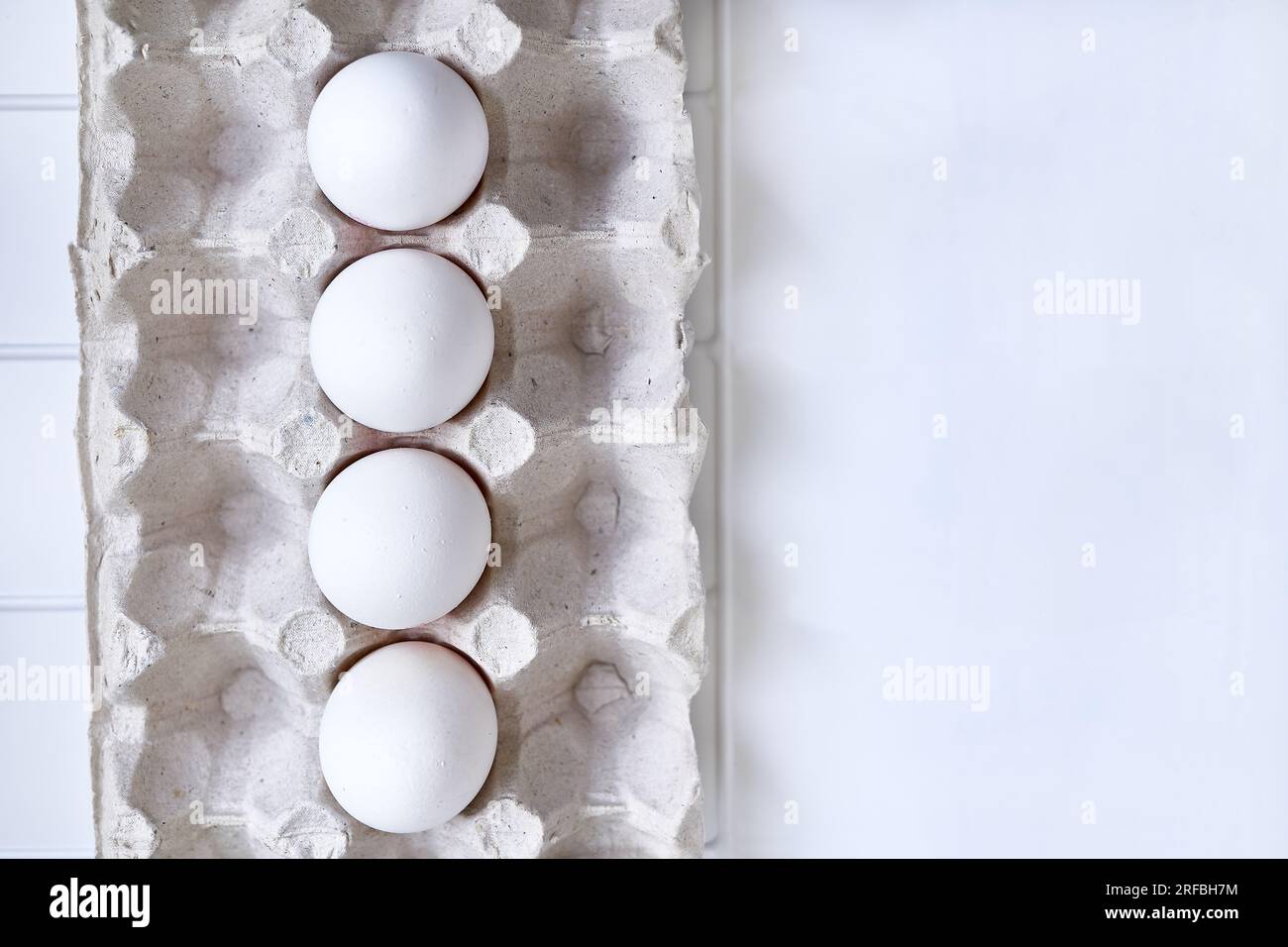 Four fresh chicken eggs on a plastic checkered shelf in package in refrigerator Stock Photo