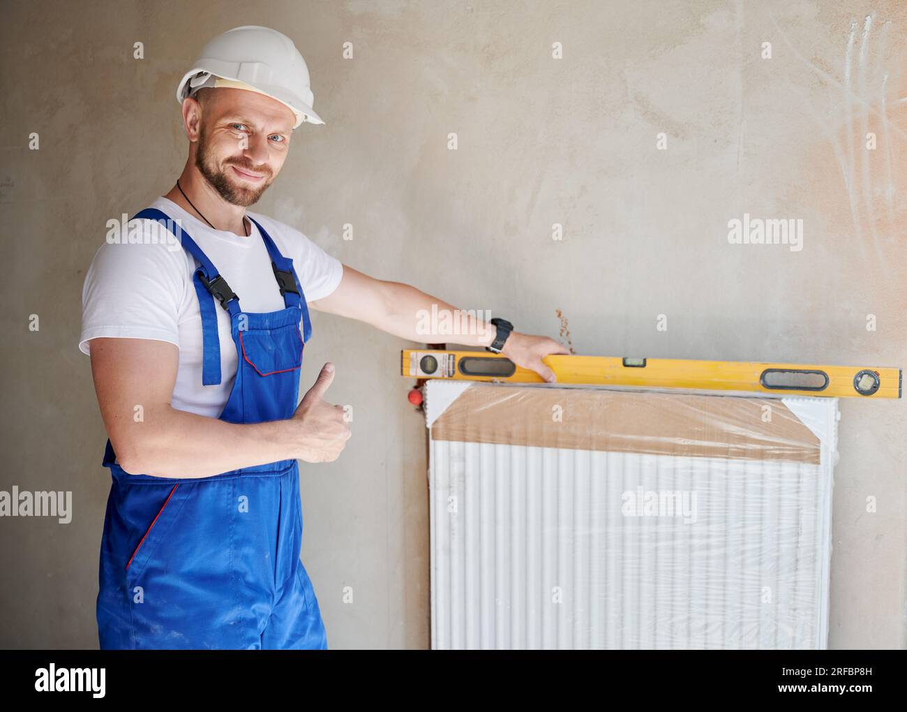 Male worker installing heating radiator in apartment under renovation ...