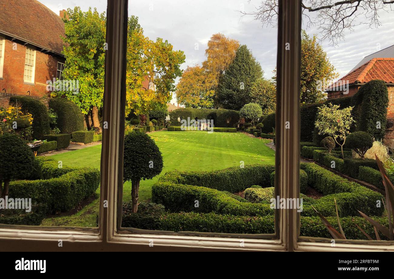 A garden triptych view through an 18C Fydell House window to the attractive walled garden Stock Photo