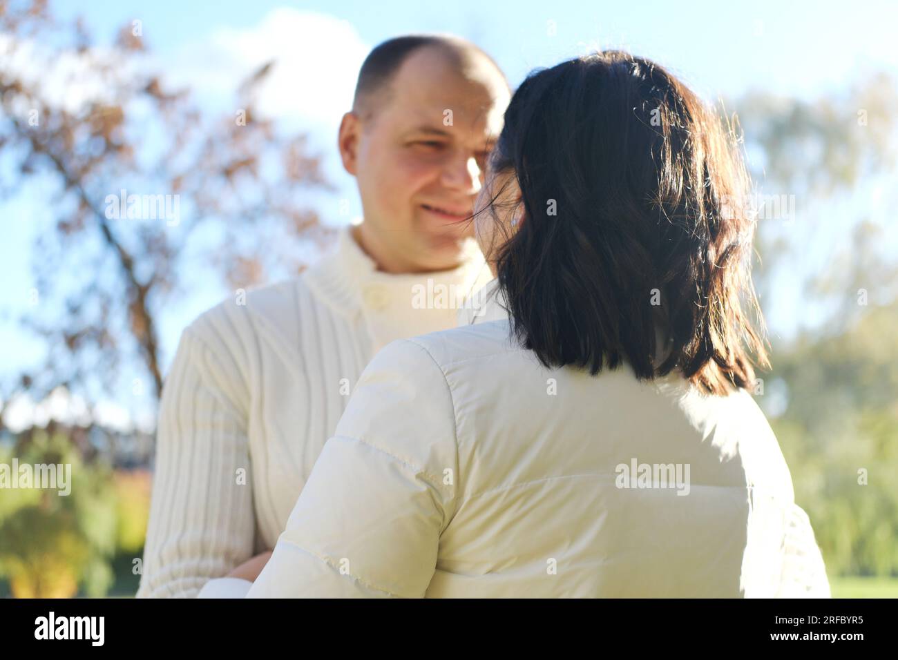 Husband and wife on a walk in the autumn park. Husband looks lovingly