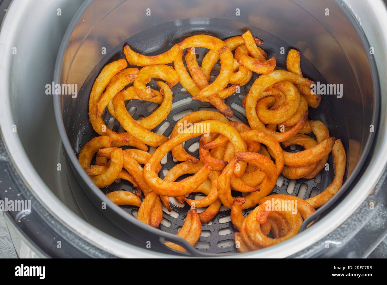 Curly fries cooked in an electric air fryer. Fast healthy alternative