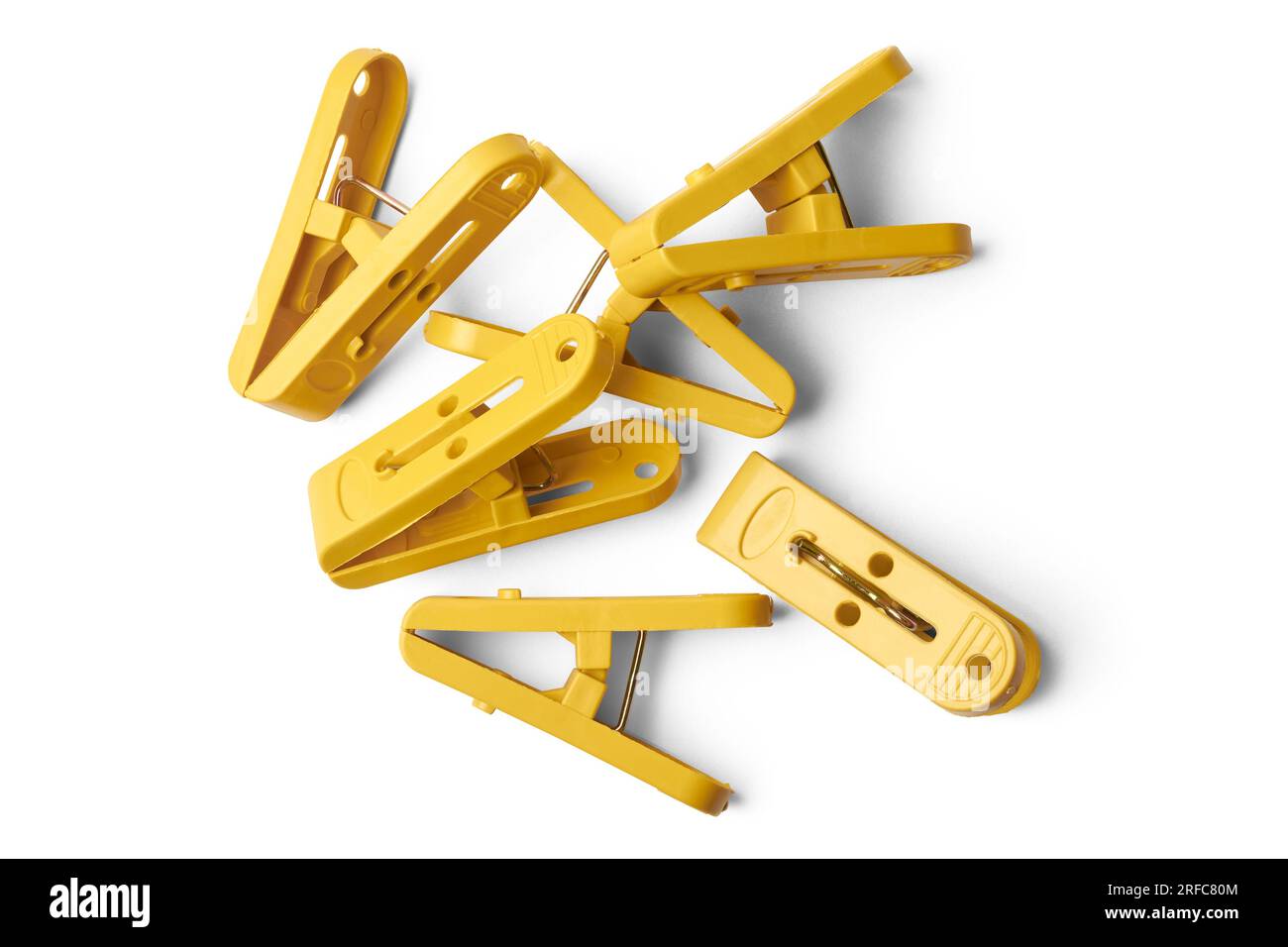 pile of yellow clips, plastic paper or laundry clips, clothespin or clothes pegs isolated on white background taken straight from above Stock Photo