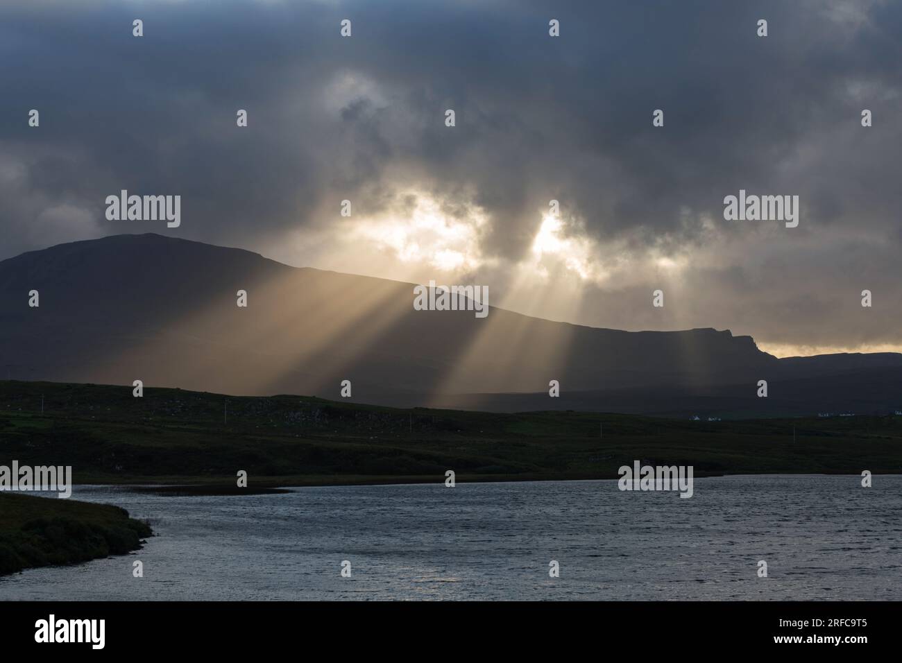 Crepuscular rays over the Trotternish Ridge and Loch Mealt, Isle of Skye, Scotland Stock Photo