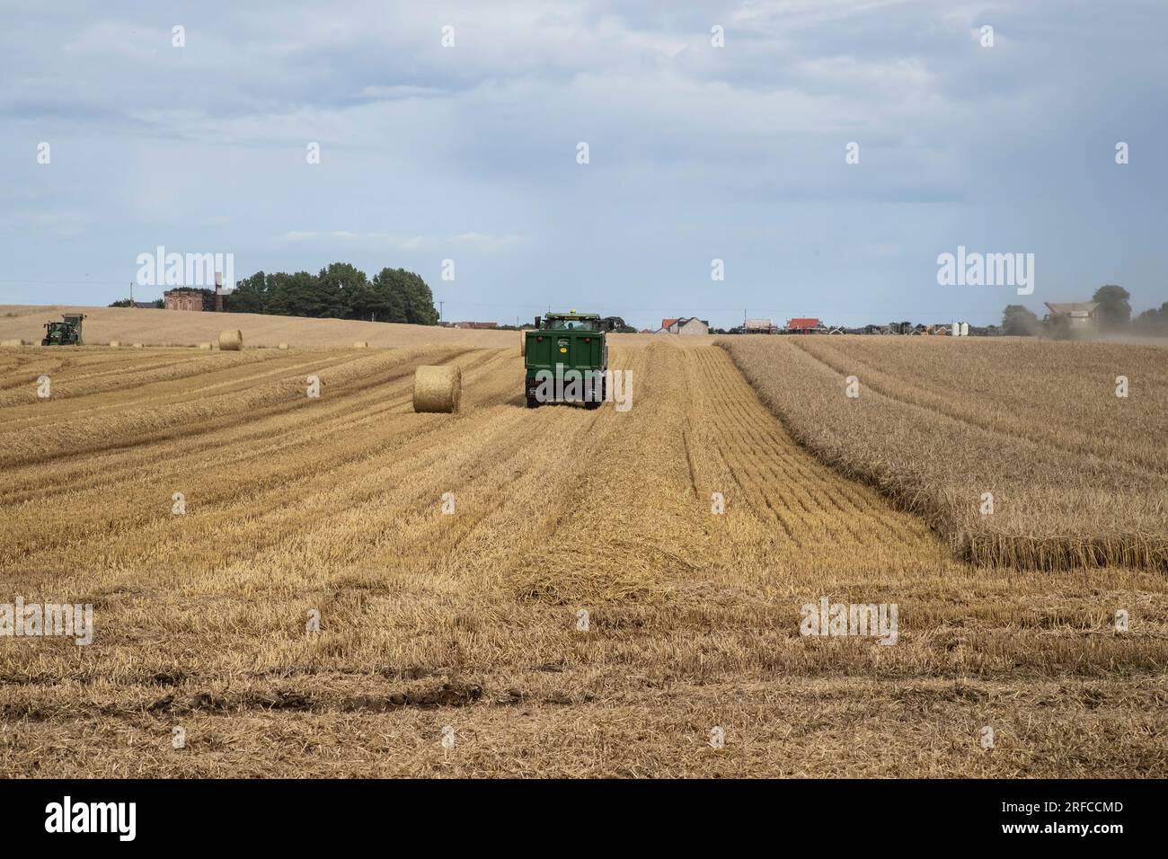 Farm machinery cutting wheat and baling hay on a summer's day in