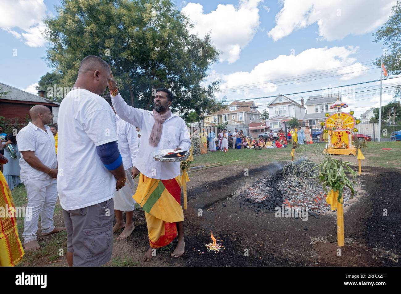 Prior to the fire walking, at the Arya Spiritual Grounds, a priest paints a tilaka on the forehead of a devout worshiper. In Jamaica, Queens, New York. Stock Photo