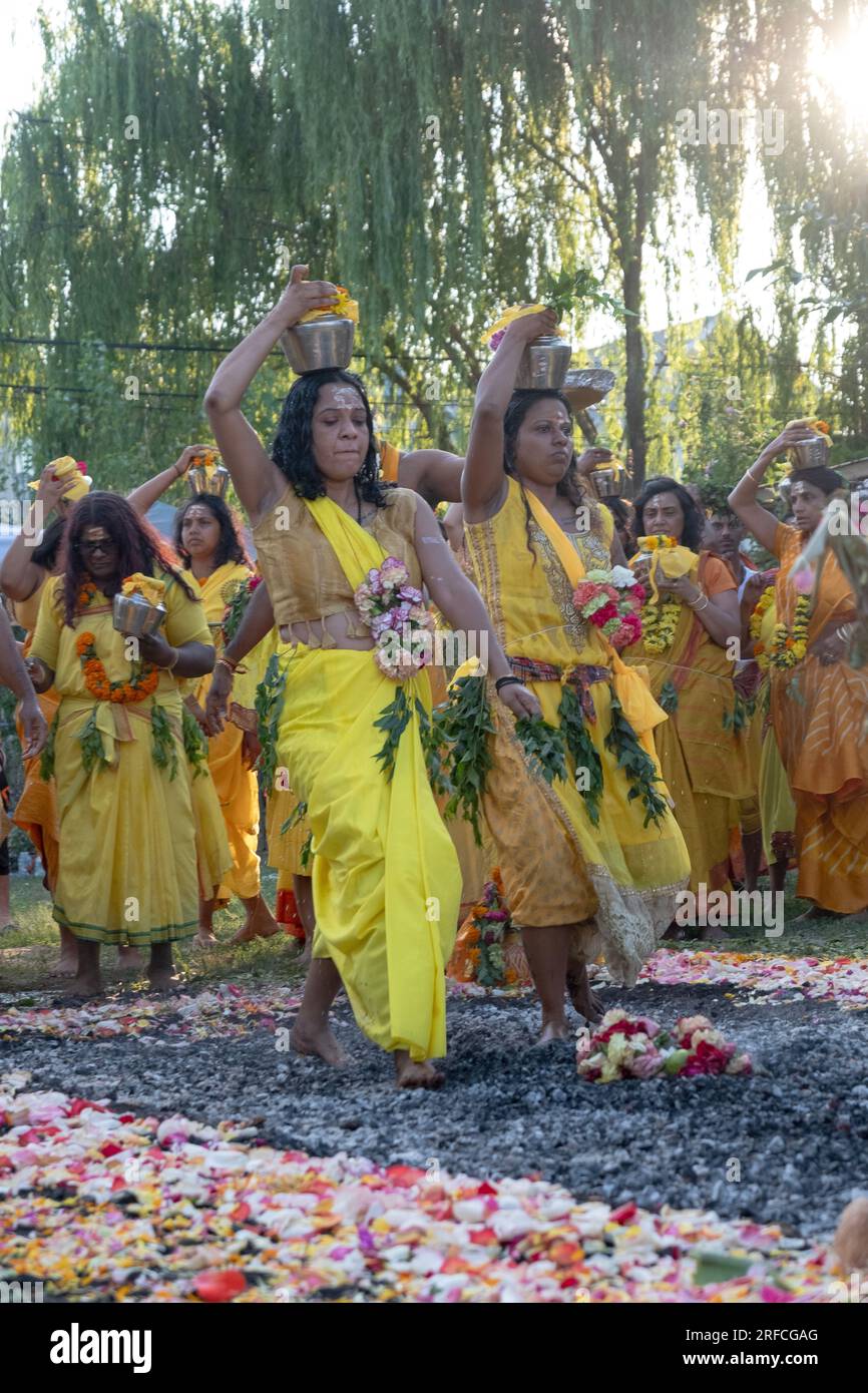 Two devout Hindu women walk barefoot on hot coals at a Thimithi fire walking event in Arya Spiritual Grounds in Jamaica, Queens, New York. Stock Photo