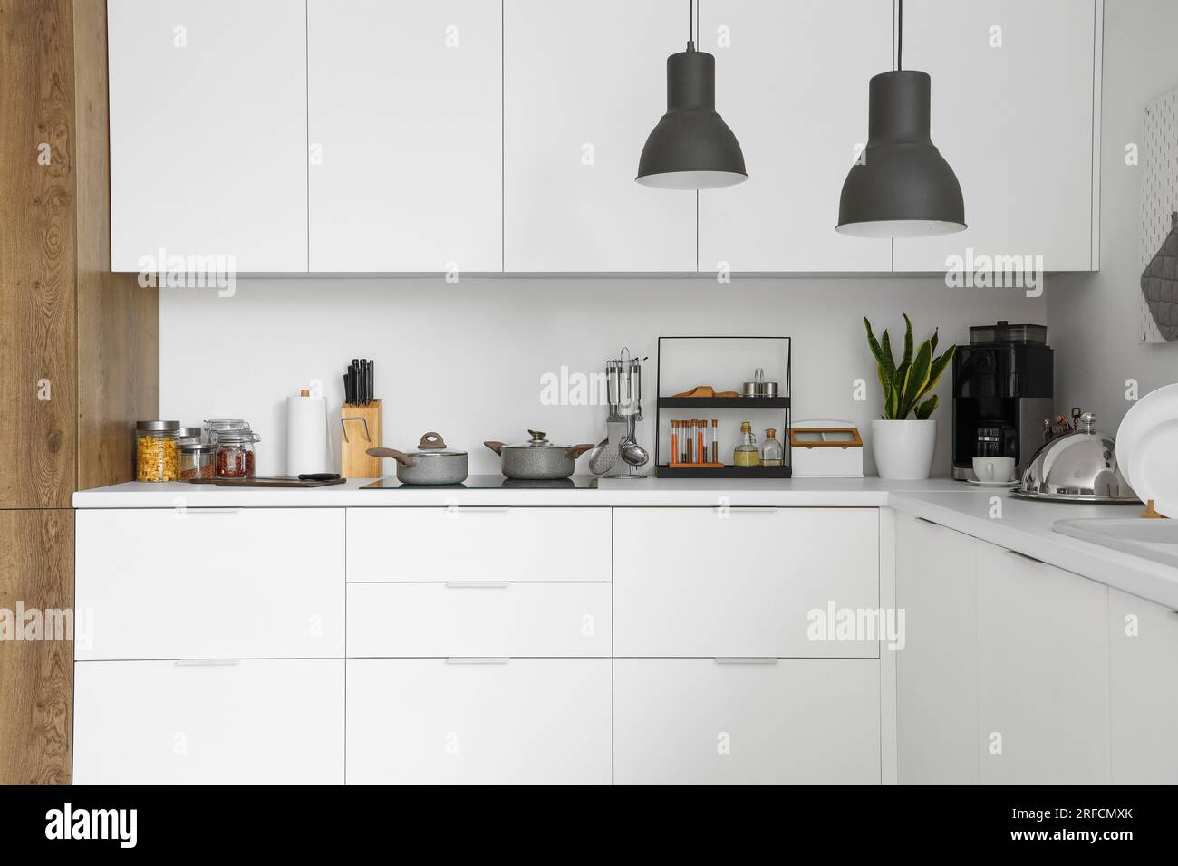 White kitchen counters with electric stove, cooking pots and utensils