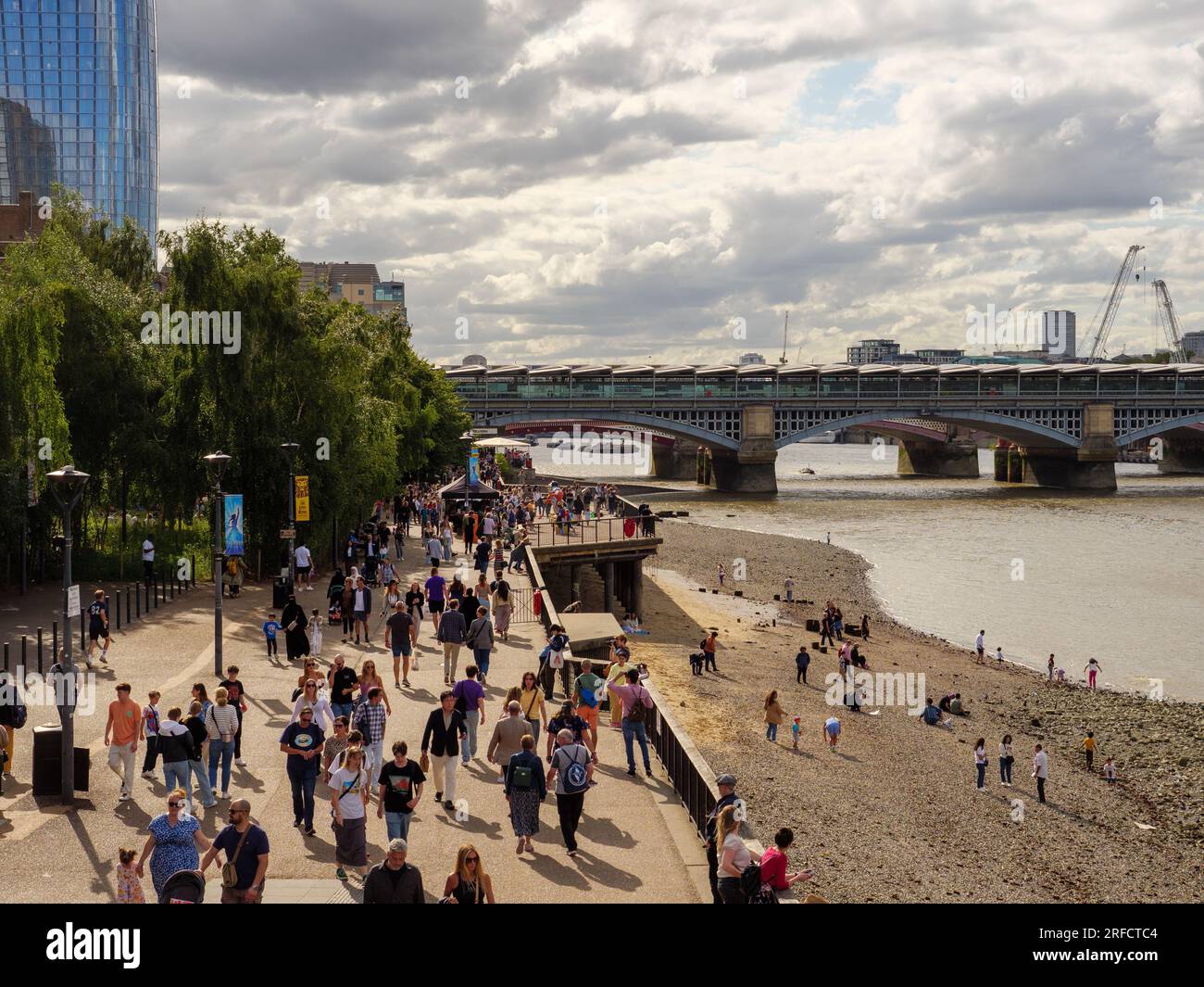 People walking along Bankside Beach beside the River Thames at low tide, London, UK Stock Photo