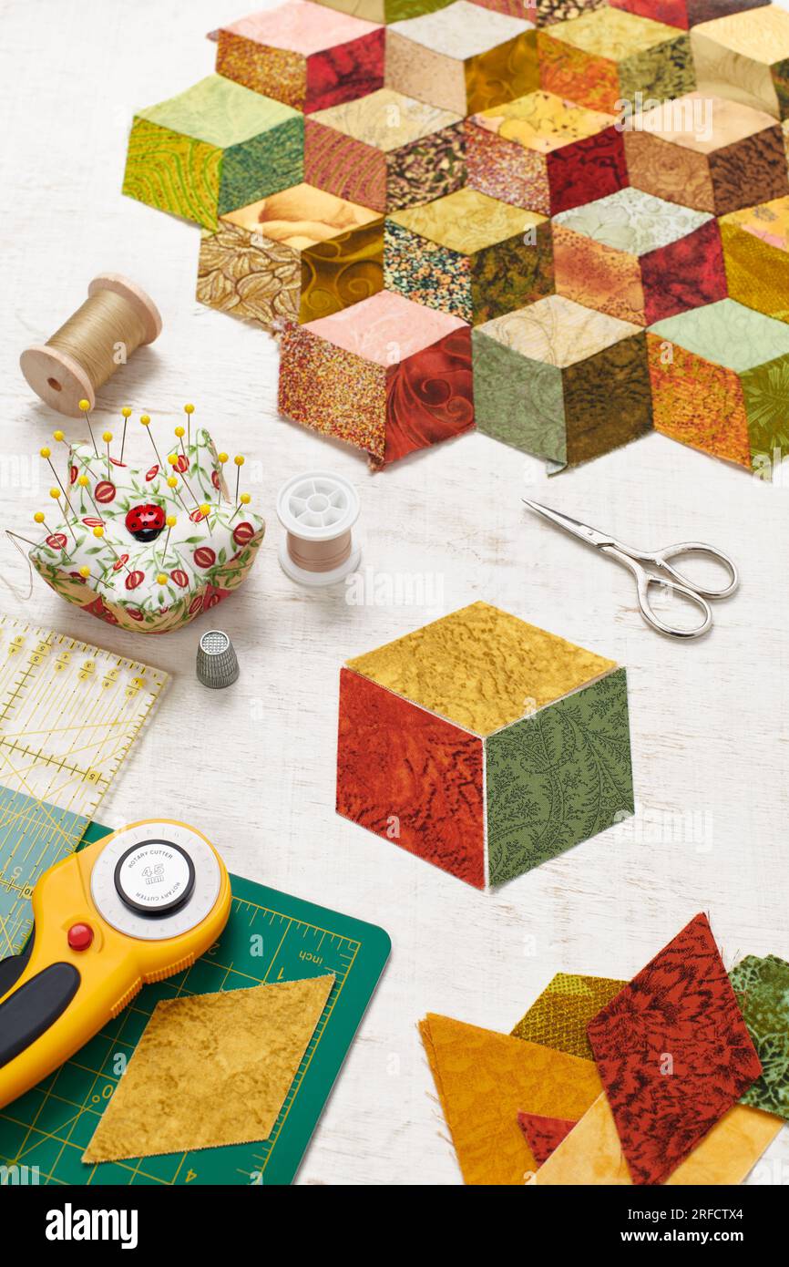 Fragment of tumbling blocks quilt, accessories for quilting on a white surface Stock Photo