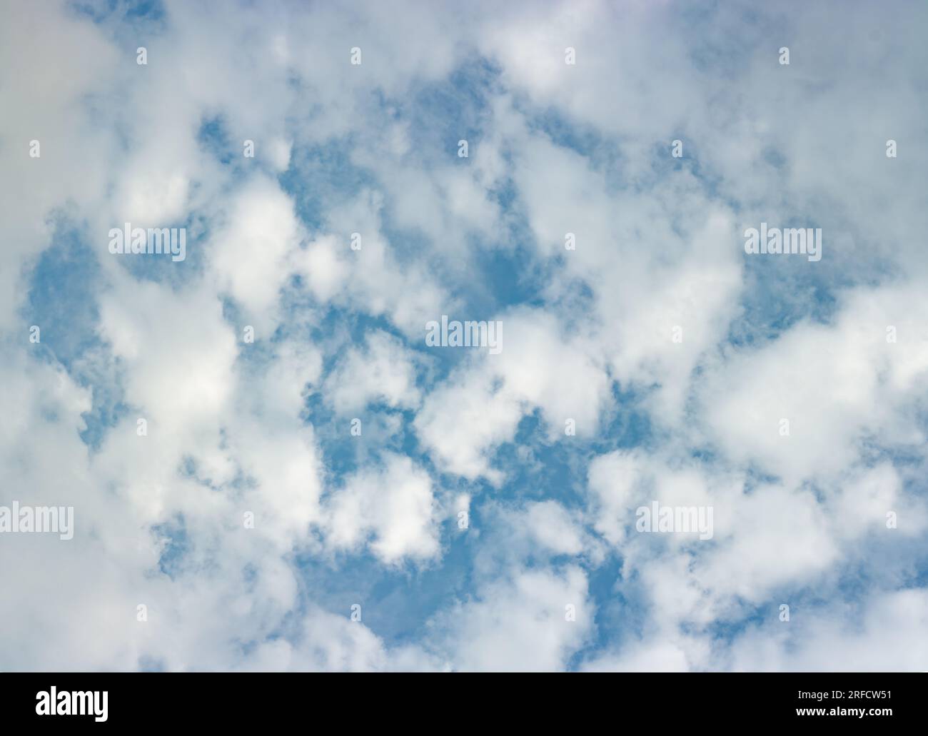 Altocumulus clouds seen through a layer of fast moving stratus clouds on a summer evening. Stock Photo