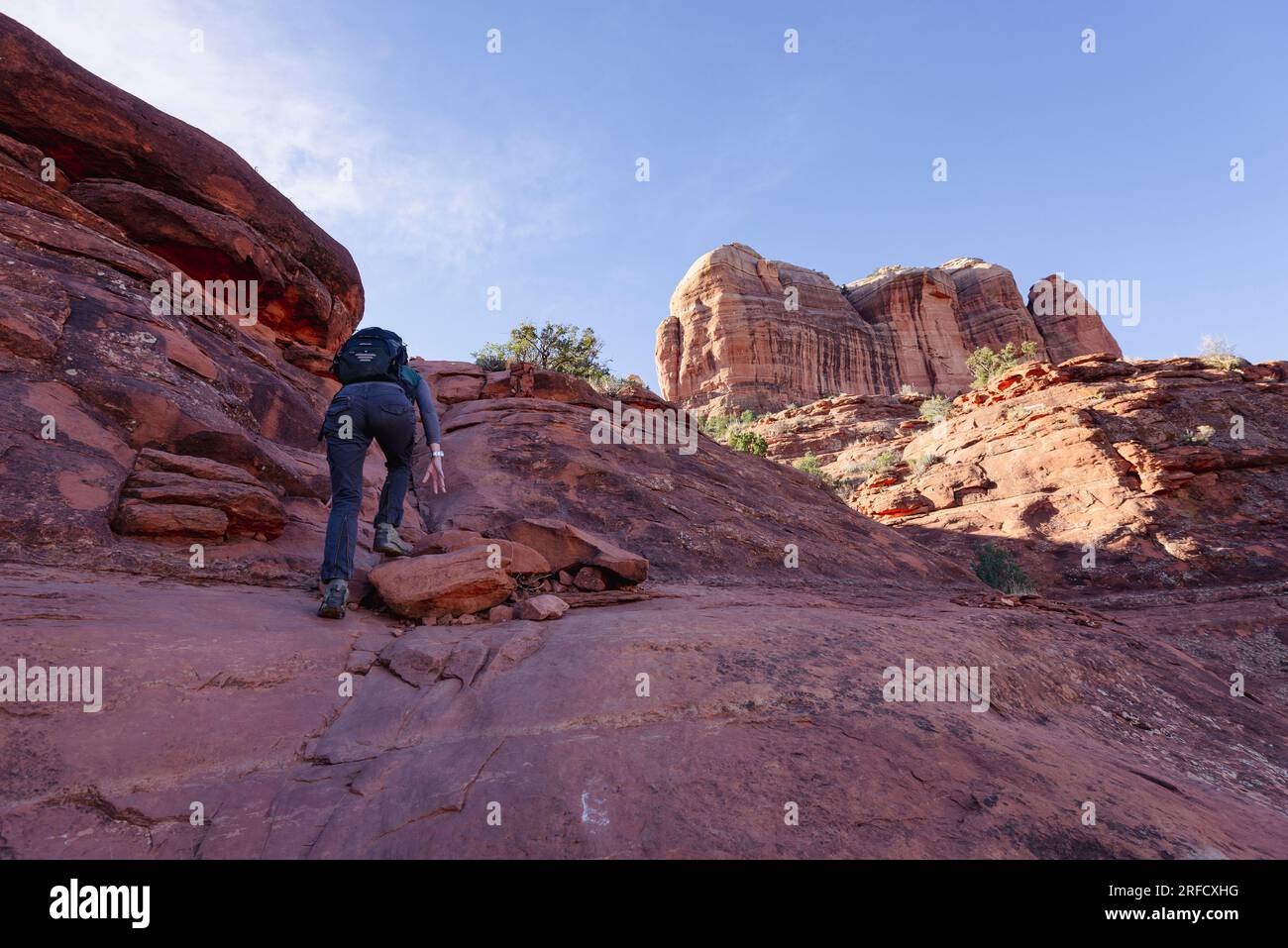 A woman climbs up the rocks towards Cathedral Rock in Sedona Arizona in the USA Stock Photo