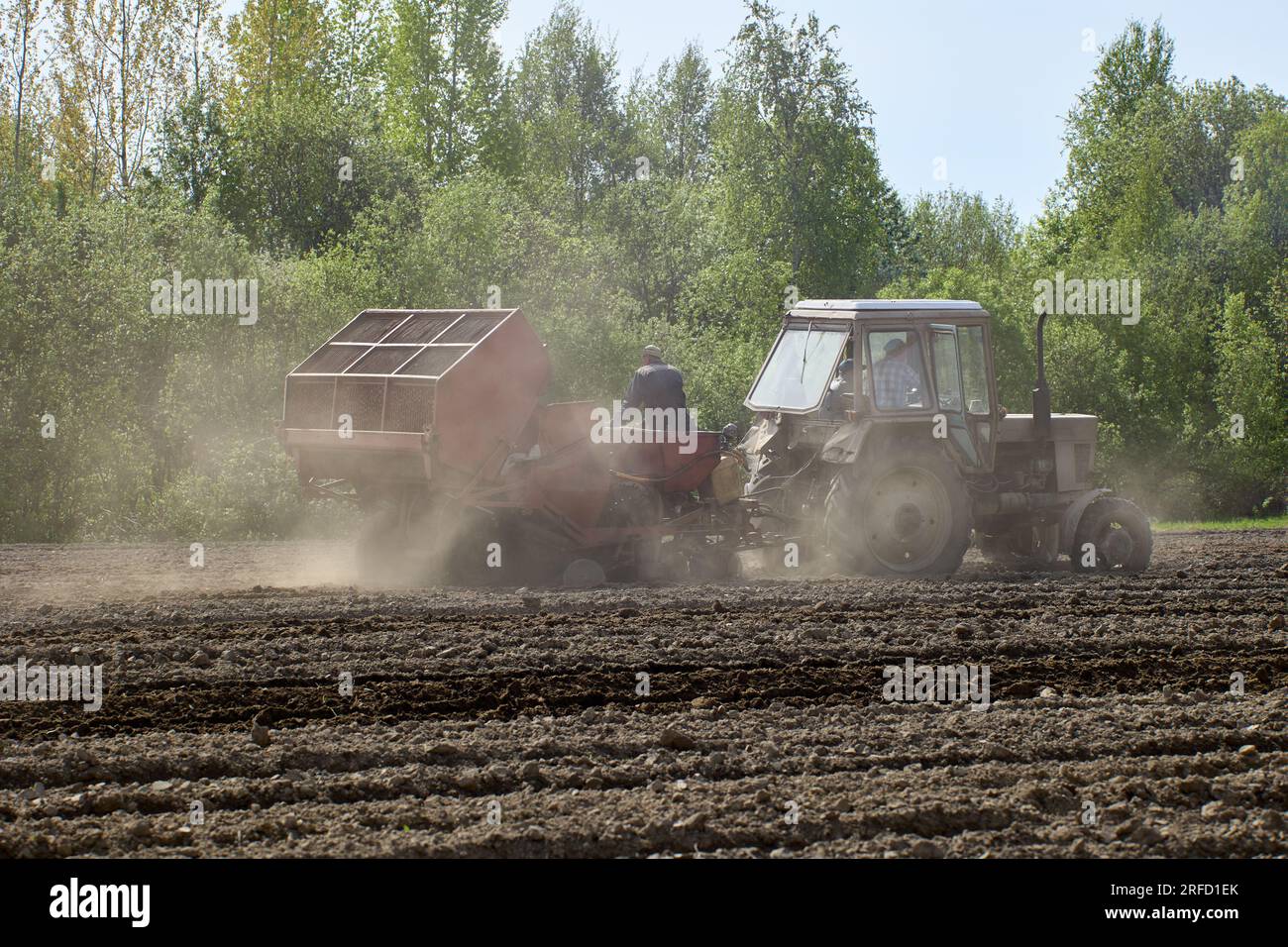 Potato planter works in farmers field as tractor trailer Stock Photo