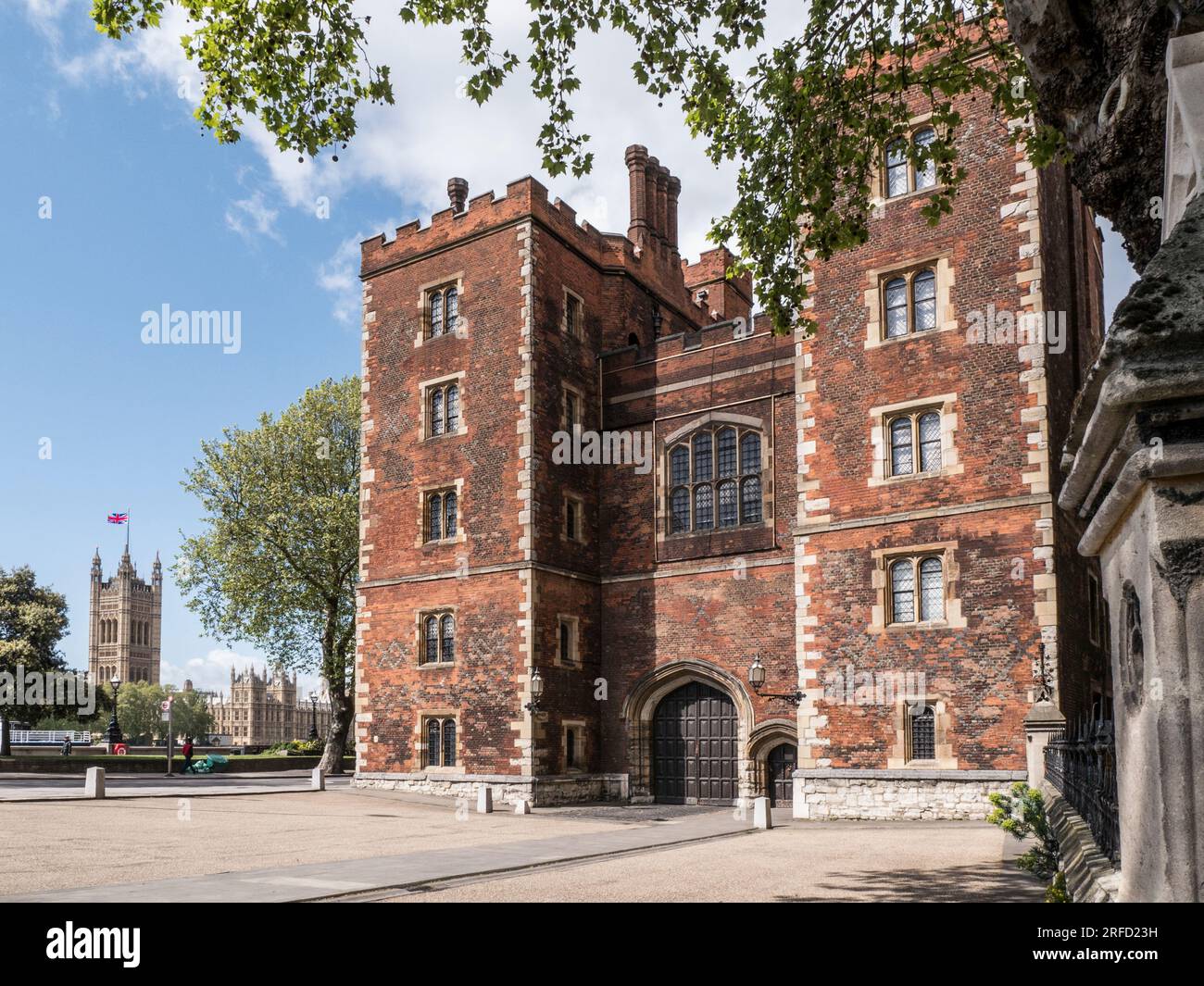 Lambeth Palace London. Morton's Tower with Houses of Parliament behind. Red brick Tudor gatehouse forming the entrance to Lambeth Palace London UK Stock Photo