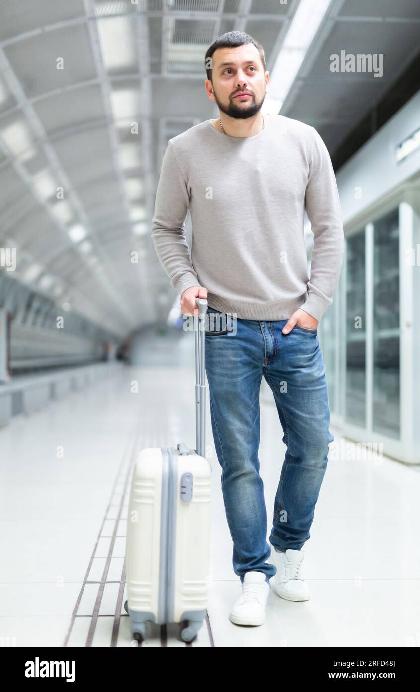 Young man walking through metro station with suitcase Stock Photo