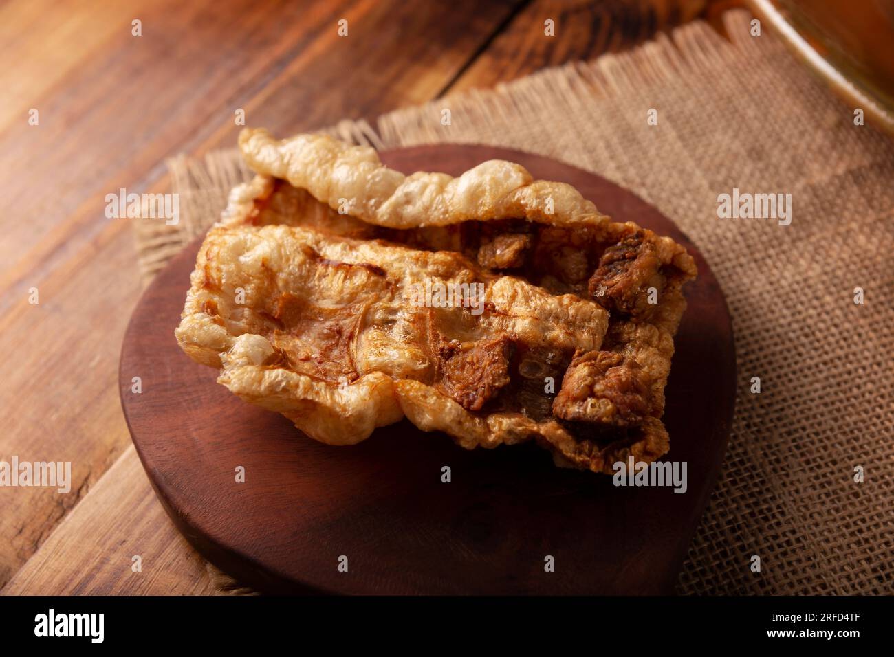 Chicharron. Crispy Fried pork rind, are pieces of aired and fried pork skin, traditional Mexican ingredient or snack served on wooden cutting board Stock Photo