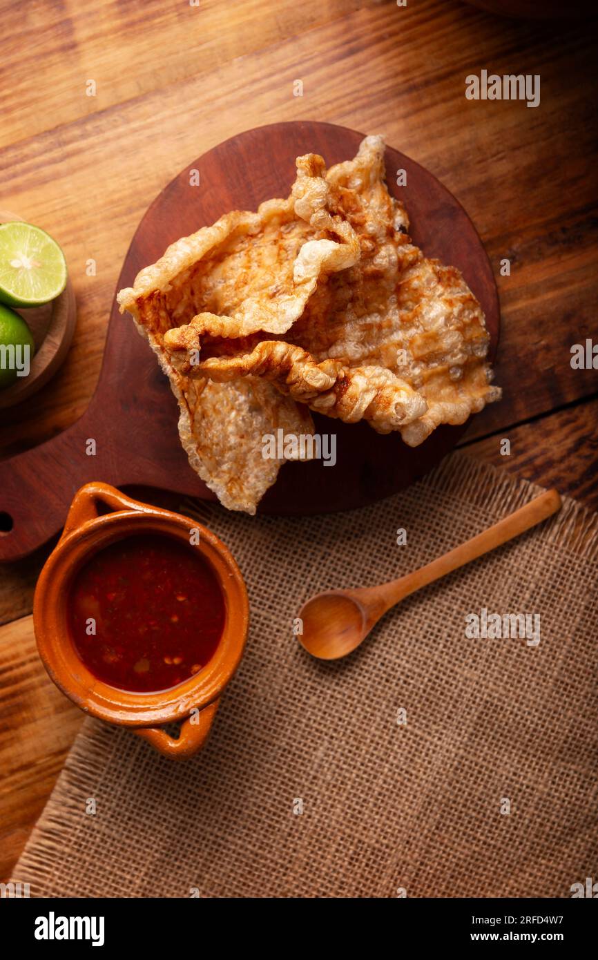 Chicharron. Crispy Fried pork rind, are pieces of aired and fried pork skin, traditional Mexican ingredient or snack served with lime juice and red ho Stock Photo